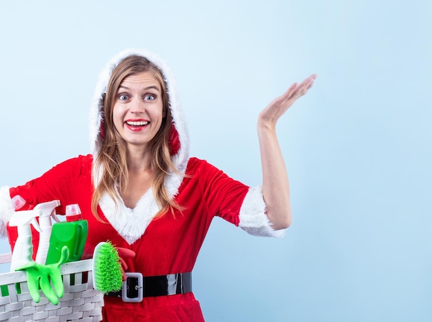 Primo piano della donna felice caucasica che indossa abiti da Babbo Natale e guanti per la pulizia che tengono il cestino con spray per la pulizia