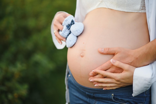 Primo piano della donna incinta con le mani sulla pancia sullo sfondo della natura