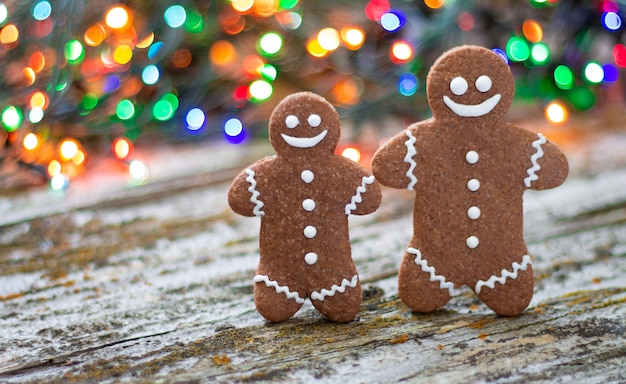 Primo piano della famiglia dell'uomo di pan di zenzero di natale sulla tavola di legno con il fondo del bokeh