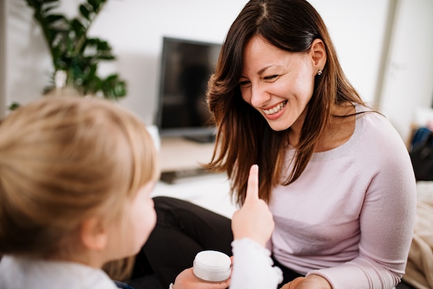 Primo piano della figlia che mette crema sul fronte della madre a casa