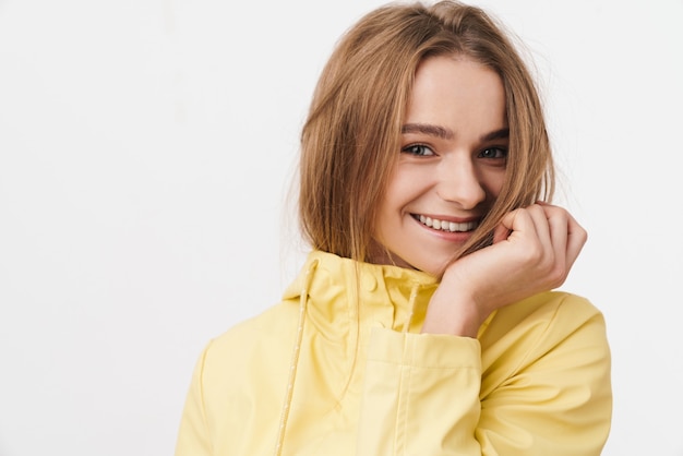 Primo piano della foto di una giovane donna divertente in impermeabile che guarda l'obbiettivo e sorride