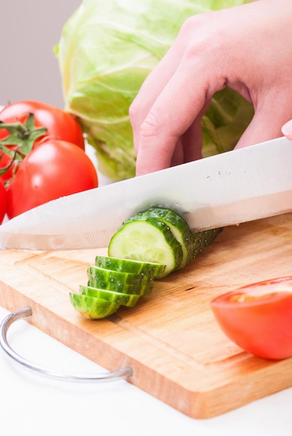 Primo piano della giovane donna nelle verdure di taglio della cucina