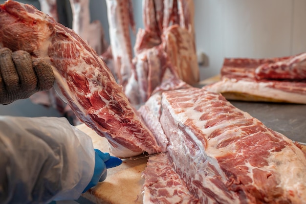 primo piano della lavorazione della carne nell'industria alimentare il lavoratore taglia lo stoccaggio di maiale crudo in frigorifero