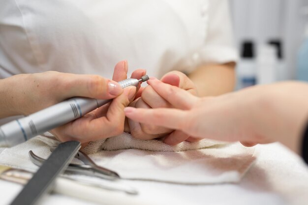 Primo piano della manicure che fa la manicure hardware a una giovane bella ragazza nel salone spa