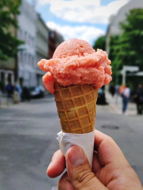 Primo piano della mano che tiene il cono gelato