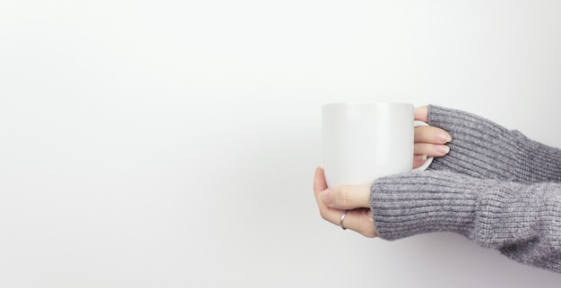 Primo Piano Della Mano Che Tiene La Tazza Di Tè Bianca Su Sfondo Bianco. Tenendo una tazza bianca di caffè caldo.