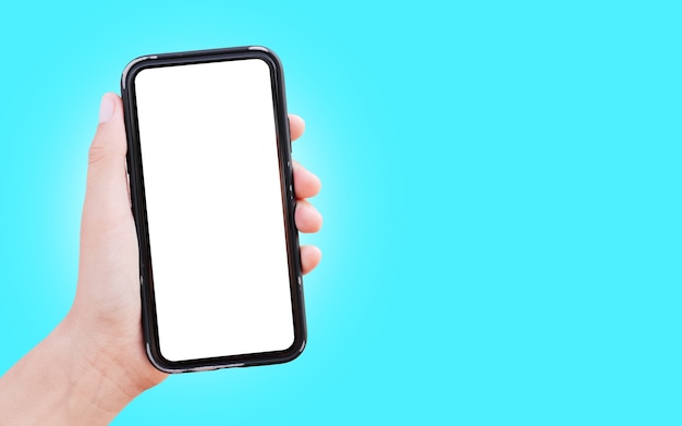 Primo piano della mano che tiene smartphone con mockup bianco isolato sulla superficie di colore ciano.