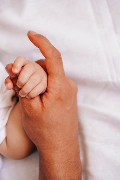 Primo piano della mano del bambino della tenuta del padre sul foglio bianco Paternità felice