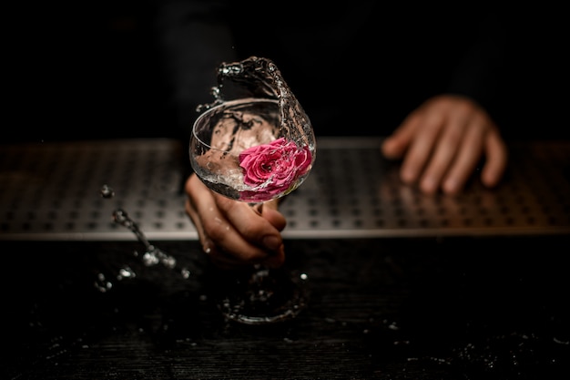 Primo piano della mano del barista con cocktail con fiore