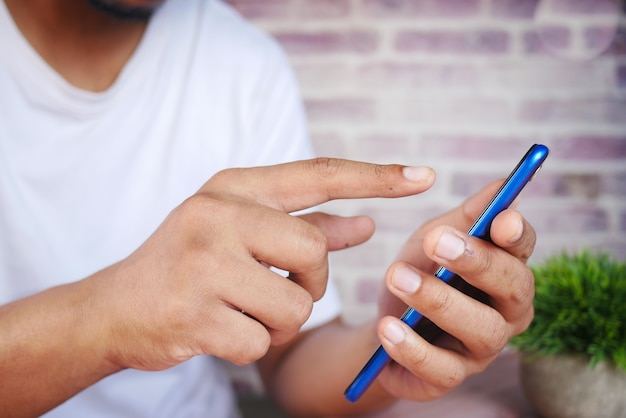 Primo piano della mano del giovane che utilizza lo smartphone