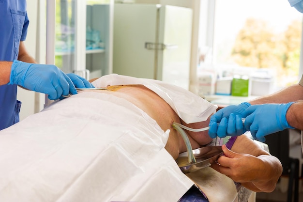 Primo piano della mano del medico mentre il chirurgo e l'assistente eseguono un intervento chirurgico sul team medico utilizzando vari strumenti chirurgici in sala operatoria