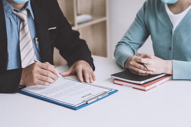 Primo piano della mano dell'imprenditore che tiene una penna per controllare i curricula dei candidati al lavoro in ufficio.