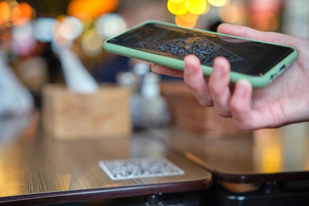 Primo piano della mano dell'ospite che ordina il pasto al ristorante durante la scansione del codice qr con il telefono cellulare per il menu online.