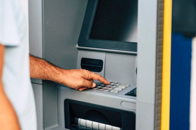 Primo piano della mano dell'uomo che preleva denaro al bancomat automatico digitando il numero di codice segreto di sicurezza Concetto di attività bancaria e lavoro d'affari Persone e bancomat all'aperto