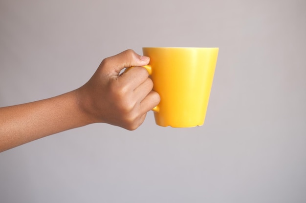 Primo piano della mano dell'uomo che tiene la tazza di colore giallo