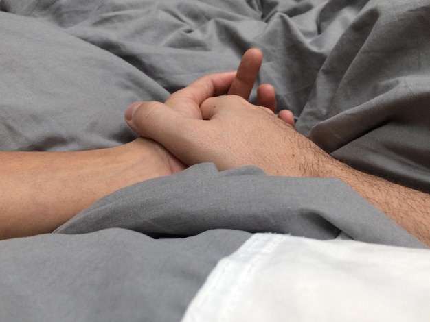 Primo piano della mano dell'uomo sul letto