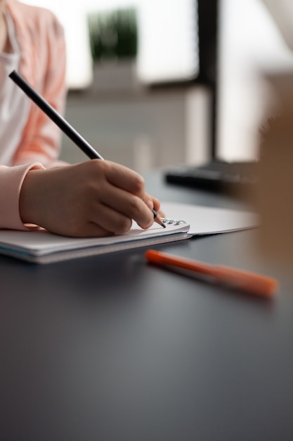 Primo piano della mano della bambina che scrive sul taccuino