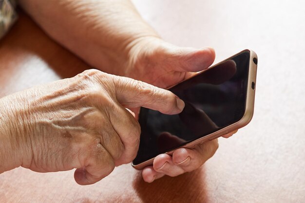 Primo piano della mano della donna anziana che digita sullo smartphone