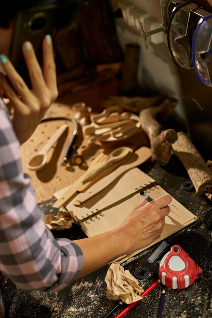 Primo piano della mano della donna del carpentiere prende appunti sui dettagli dell'ordine con il suo cliente