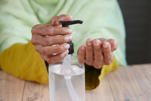 Primo piano della mano delle donne anziane che utilizza gel igienizzante per prevenire il virus