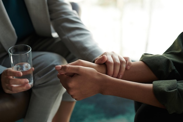 Primo piano della mano dello psicologo professionista confortante paziente femminile