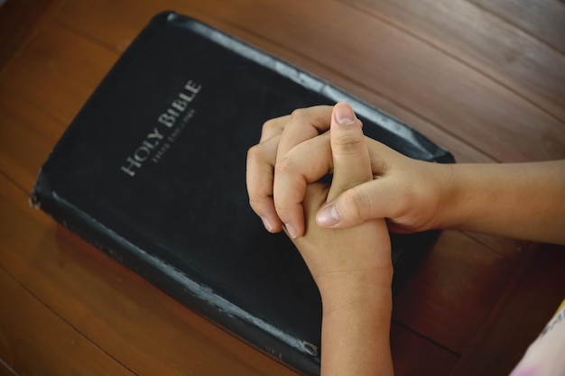 Primo piano della mano di preghiera con la Bibbia Libro spirituale che prega i concetti studiando le Sacre Scritture