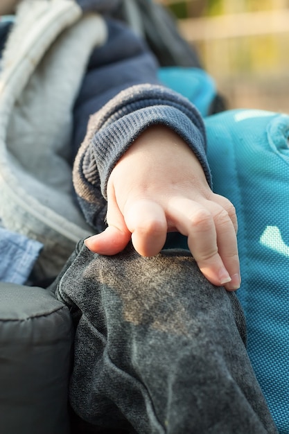 Primo piano della mano di un bambino inginocchiato su una sedia a rotelle. concetto di bambini con disabilità.