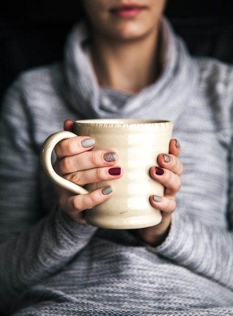 Primo piano della mano di una donna che tiene una tazza di caffè caldo. moda, tempo libero