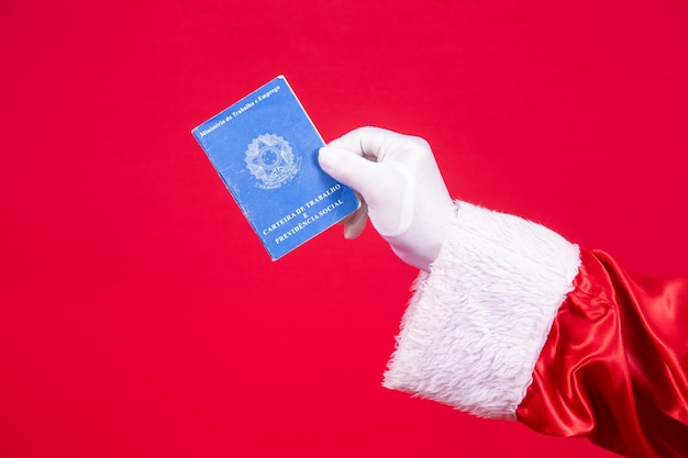 Primo piano della mano guantata di Babbo Natale che tiene una carta di lavoro brasiliana.