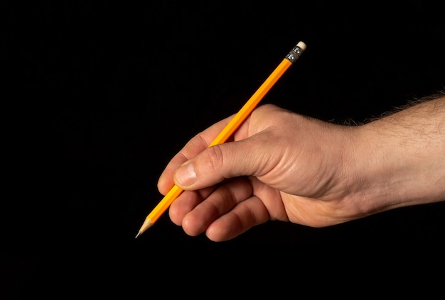 Primo piano della mano maschio che tiene la matita nera su sfondo isolato