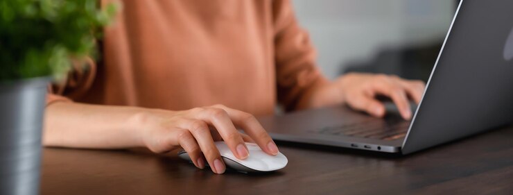 Primo piano della mano premere il pulsante del mouse del computer e utilizzare il laptop sul tavolo.