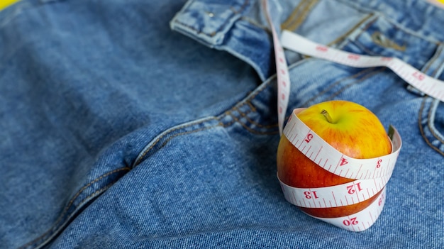 Primo piano della mela rossa su blue jeans Avvolto intorno a un metro a nastro