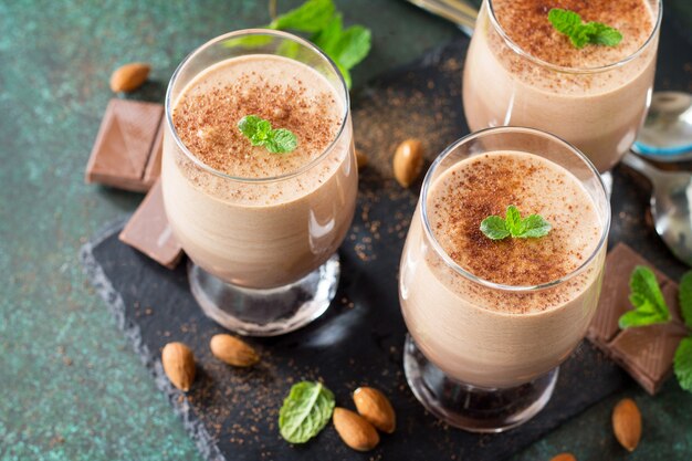 Primo piano della mousse al cioccolato con menta in bicchieri da porzione su uno sfondo di pietra o ardesia