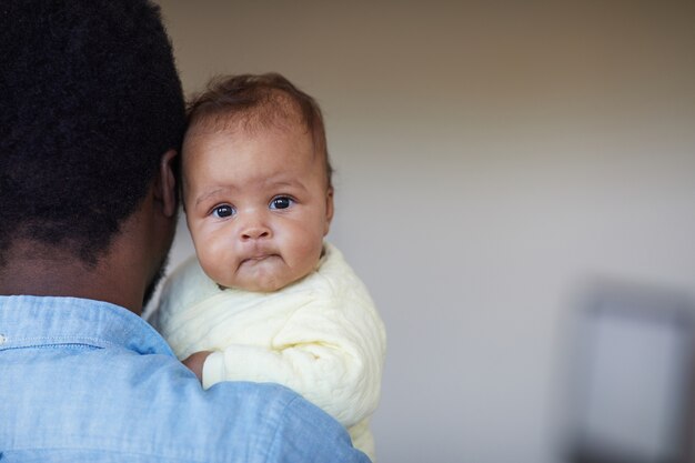 Primo piano della neonata africana sveglia sulle mani di suo padre