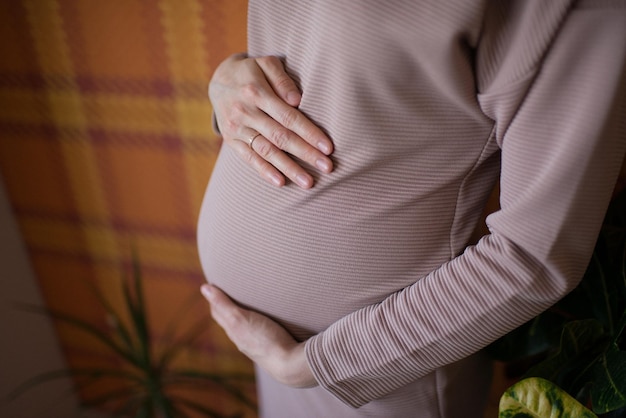 Primo piano della pancia incinta, che abbraccia le mani delle donne