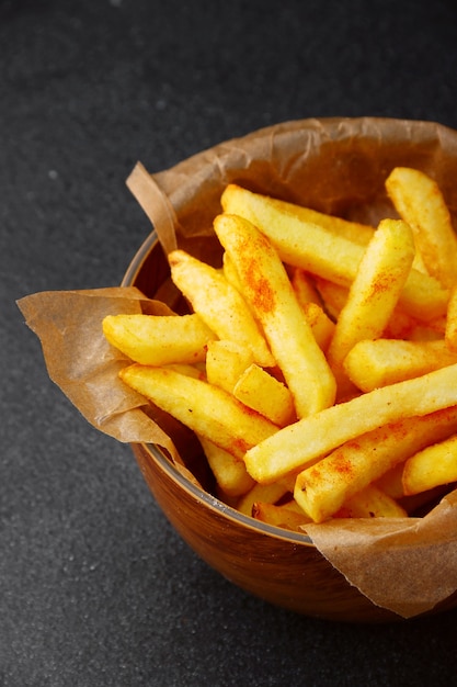 Primo piano della patata fritta. patatine fritte sulla ciotola di legno sul tavolo di cemento scuro.