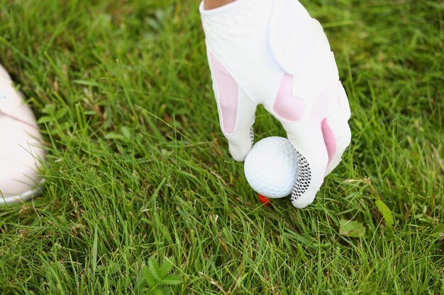 Primo piano della persona che raccoglie il guanto protettivo bianco e rosa della pallina da golf sull'attrezzatura del giocatore per