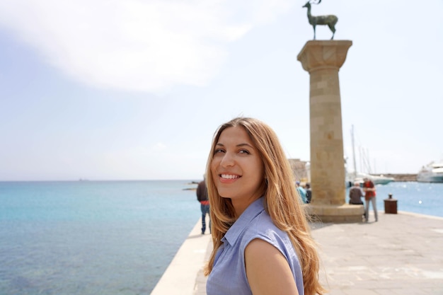 Primo piano della ragazza felice con il punto di riferimento della statua dei cervi della città di Rodi in Grecia
