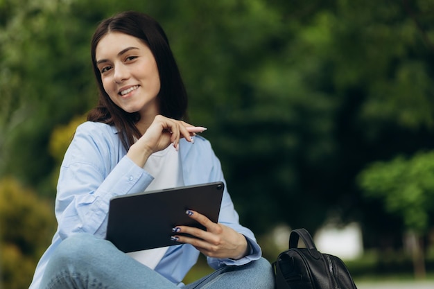 Primo piano della ragazza felice nell'utilizzo del tablet pc nel parco