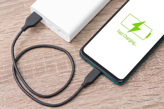 Primo piano della ricarica del telefono tramite power bank Iscrizione di ricarica rapida sullo schermo dello smartphone Ricarica del telefono con un moderno powerbank veloce