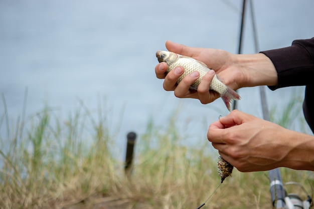 Primo piano della ruota della canna da pesca, uomo che pesca con una bellissima alba dietro di lui