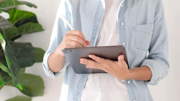 Primo piano della scrittura a mano dell'uomo su tablet digitale mentre si lavora a casa, studio online, telecomunicazioni