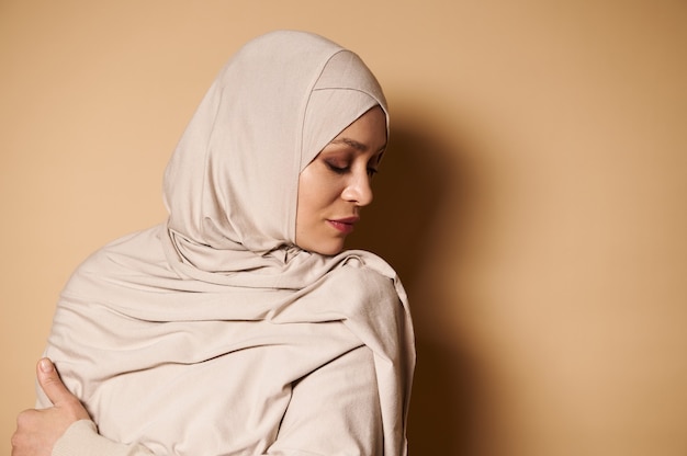 Primo piano della serena elegante donna araba musulmana nel tradizionale abito formale guardando verso il basso