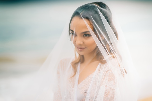 Primo piano della sposa sotto un velo su uno sfondo di cielo azzurro e mare nero
