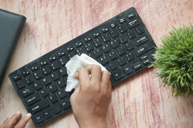 Primo piano della tastiera per la pulizia delle mani della persona con un panno