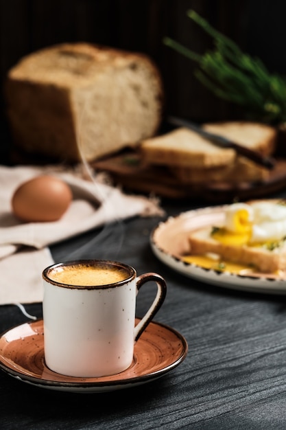 Primo piano della tazza di caffè espresso con vapore in aumento sulla tavola di legno nera