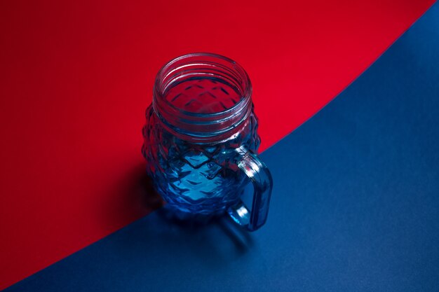 Primo piano della tazza di vetro per il succo sulla superficie scura di colore rosso e blu