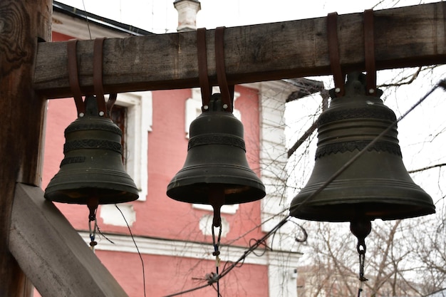 Primo piano delle campane. Le campane sono sospese ad una trave di legno. Campane con motivi metallici.