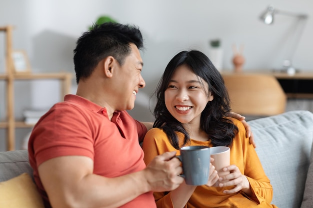Primo piano delle coppie asiatiche amorose felici che bevono insieme il tè