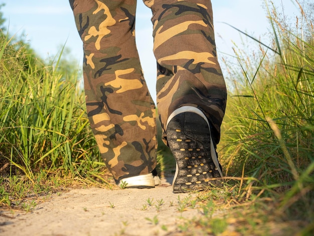 Primo piano delle gambe di un uomo vestito con scarpe da ginnastica che cammina lungo un sentiero nella foresta Il concetto di escursionismo a piedi e uno stile di vita sportivo vista posteriore